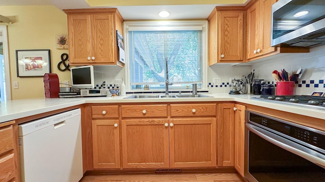 kitchen with a sink, decorative backsplash, appliances with stainless steel finishes, and light countertops