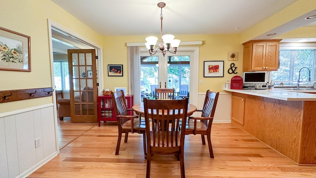 dining space with a wealth of natural light, a wainscoted wall, and light wood-type flooring