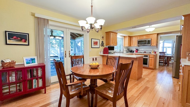 dining area featuring light wood-type flooring, an inviting chandelier, and french doors