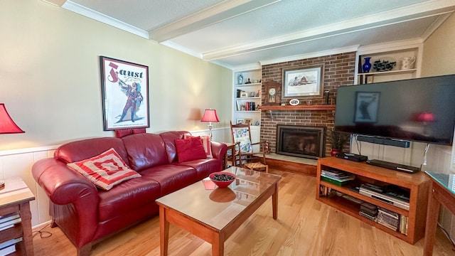 living area featuring built in shelves, crown molding, beam ceiling, a fireplace, and wood finished floors