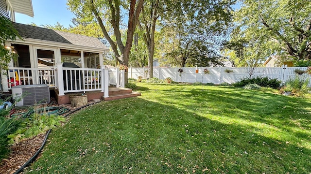 view of yard with a deck, central AC unit, a fenced backyard, and a sunroom