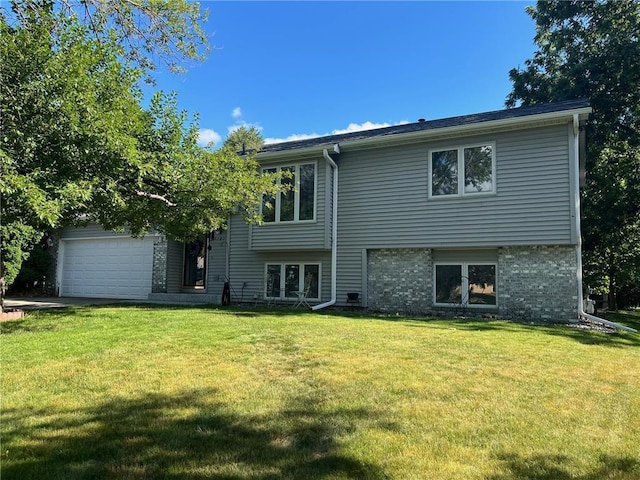 rear view of house with a yard, brick siding, and an attached garage