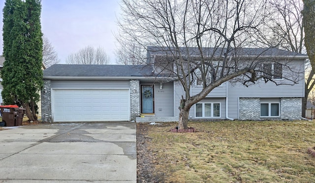 tri-level home featuring a garage, brick siding, concrete driveway, and a front yard