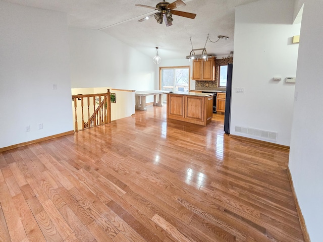 kitchen with visible vents, light countertops, light wood-type flooring, vaulted ceiling, and a ceiling fan