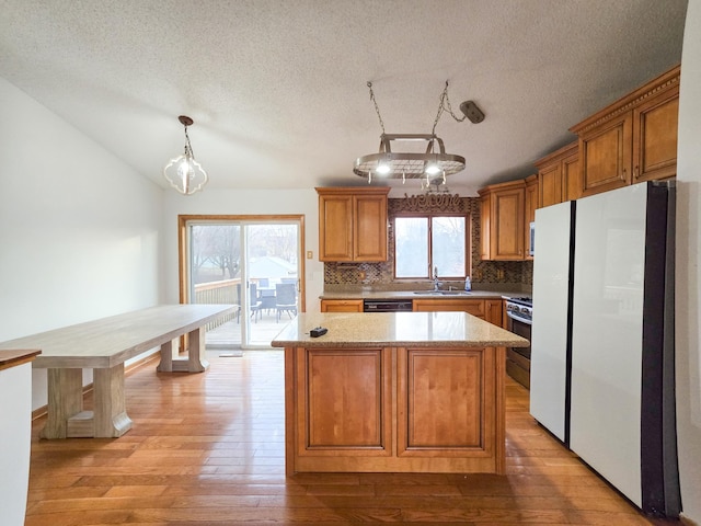 kitchen with a sink, light wood-style flooring, freestanding refrigerator, and stainless steel gas range oven