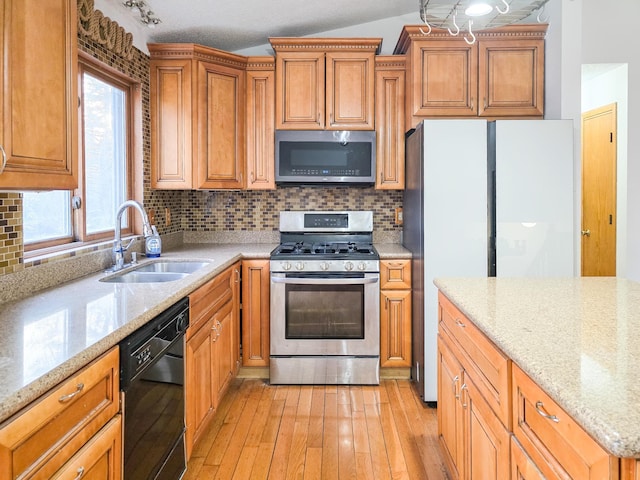 kitchen with tasteful backsplash, stainless steel appliances, light wood-type flooring, and a sink