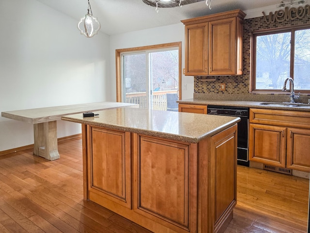 kitchen featuring a sink, brown cabinets, dishwasher, and light wood-style flooring