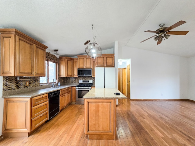 kitchen with a kitchen island, decorative backsplash, appliances with stainless steel finishes, light wood-style floors, and a sink