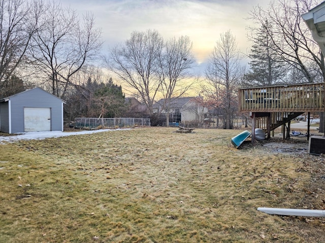 view of yard with an outbuilding, fence, central AC, a garage, and a deck