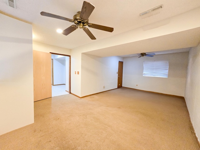 empty room with visible vents, baseboards, light colored carpet, and ceiling fan