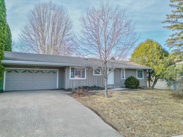 ranch-style house with driveway, an attached garage, and board and batten siding