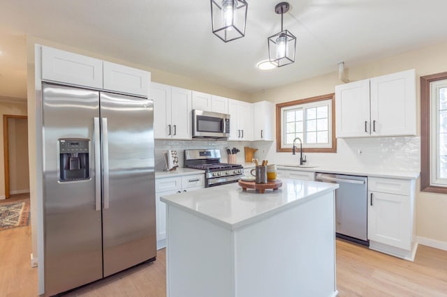 kitchen with a sink, white cabinets, light wood-type flooring, and stainless steel appliances