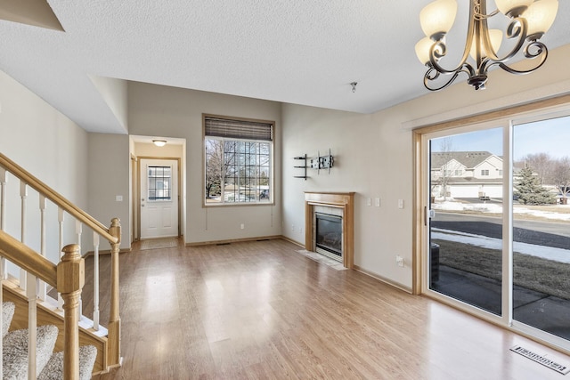 unfurnished living room with a wealth of natural light, visible vents, a fireplace with flush hearth, and light wood finished floors