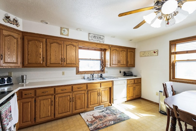 kitchen featuring dishwasher, brown cabinetry, light floors, and a sink