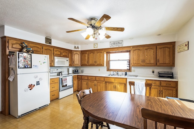 kitchen with light floors, light countertops, brown cabinets, white appliances, and a sink