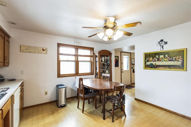 dining area featuring light floors, a textured ceiling, and baseboards