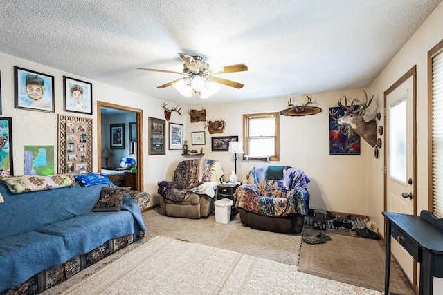 carpeted living area with a textured ceiling and a ceiling fan