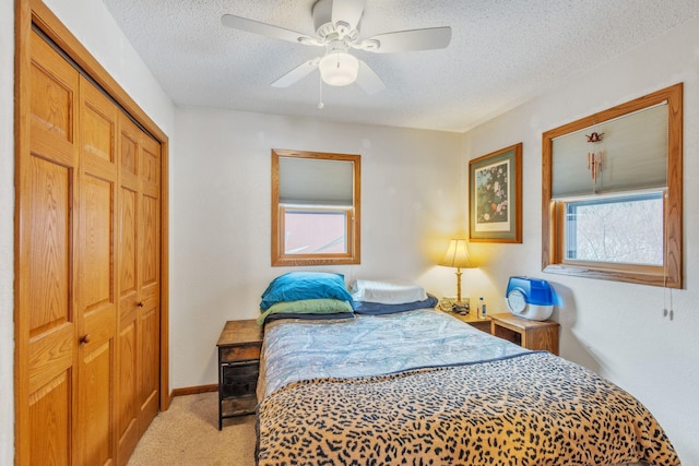 bedroom with multiple windows, light colored carpet, a closet, and a textured ceiling