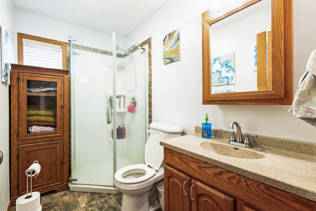 bathroom with vanity, a shower stall, and toilet