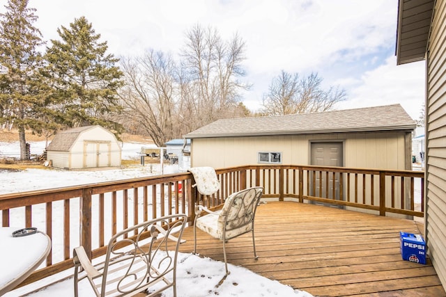 snow covered deck featuring an outbuilding and a storage shed