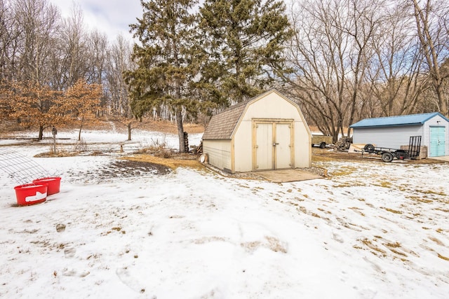 snow covered structure featuring a storage shed and an outdoor structure