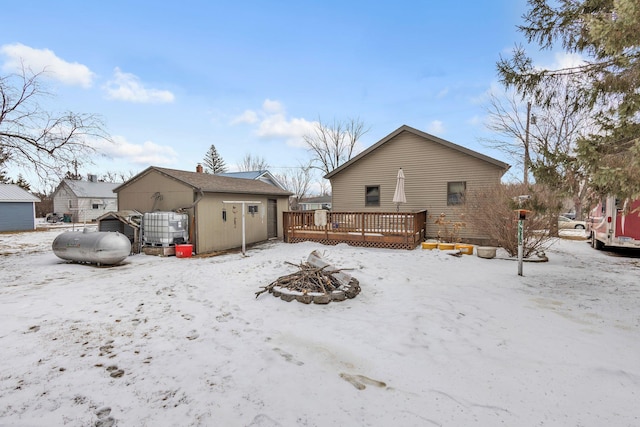 snow covered rear of property featuring a wooden deck and an outdoor fire pit