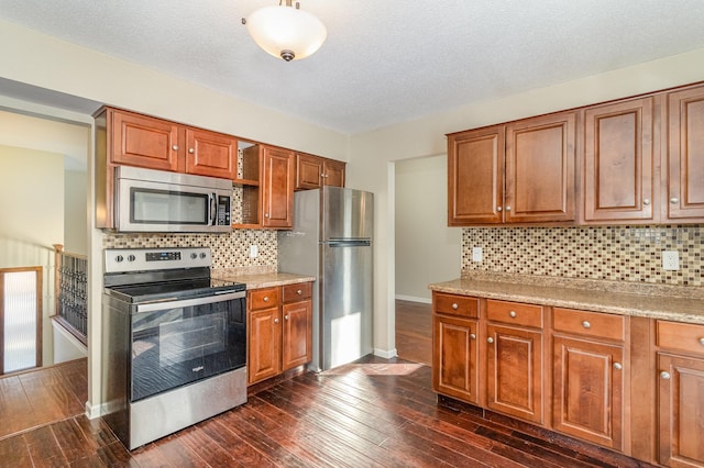 kitchen with dark wood-style floors, brown cabinets, appliances with stainless steel finishes, and baseboards