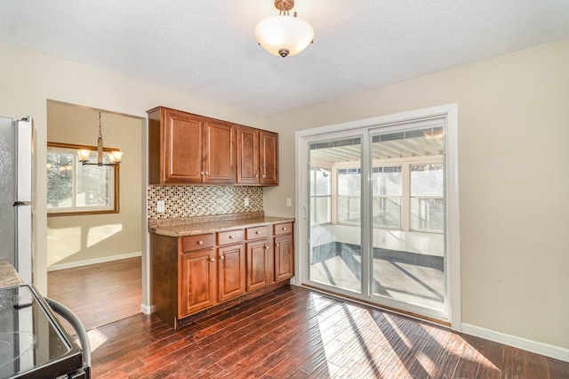 kitchen featuring brown cabinetry, decorative backsplash, freestanding refrigerator, and dark wood-type flooring