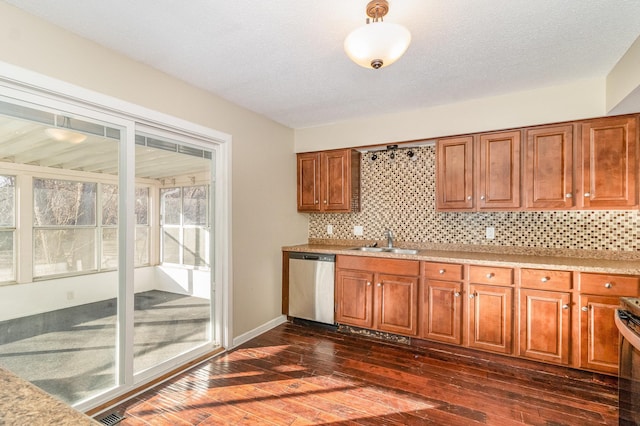 kitchen featuring light countertops, decorative backsplash, appliances with stainless steel finishes, brown cabinetry, and a sink