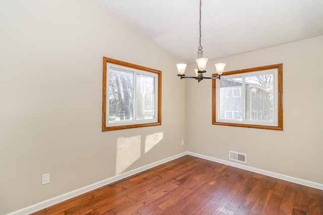 spare room with baseboards, visible vents, dark wood finished floors, vaulted ceiling, and a notable chandelier