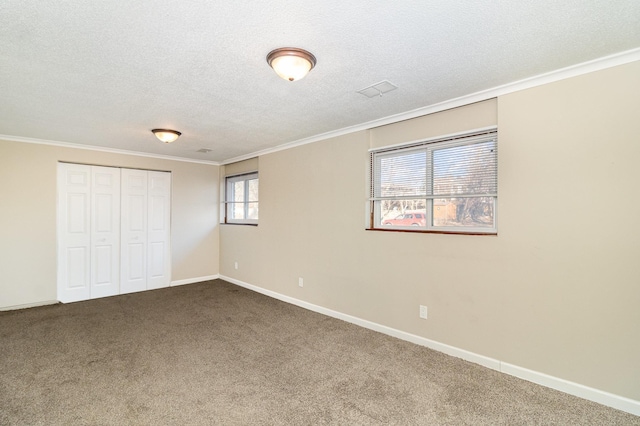 unfurnished bedroom featuring ornamental molding, a textured ceiling, a closet, carpet, and baseboards