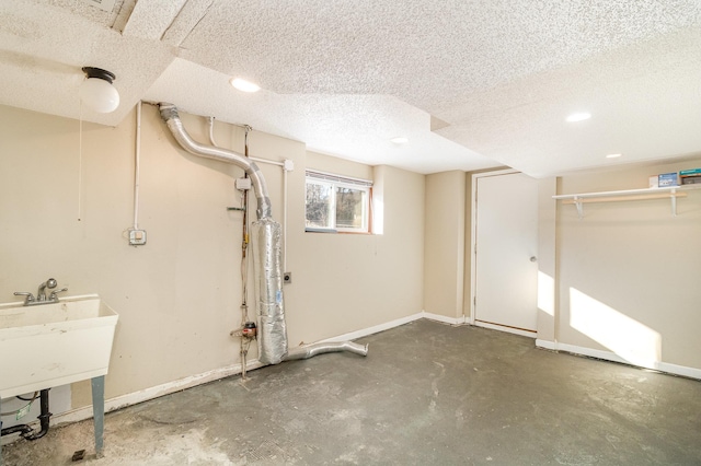 basement with a textured ceiling, baseboards, and a sink