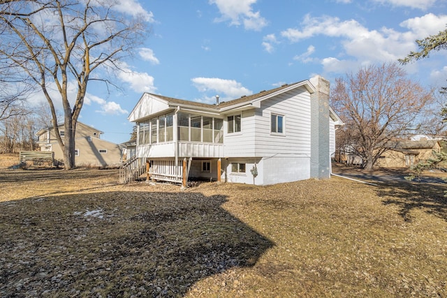 back of house with stairs, a sunroom, and a chimney