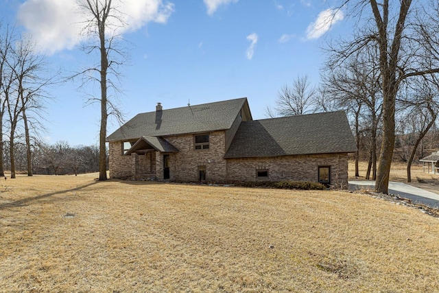 view of side of property with a chimney, a yard, and a shingled roof