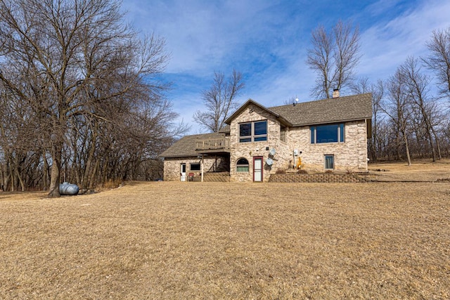 view of front of house featuring a front lawn, stone siding, and a chimney