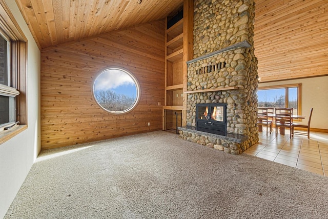 unfurnished living room with tile patterned floors, carpet floors, wood walls, a fireplace, and wood ceiling