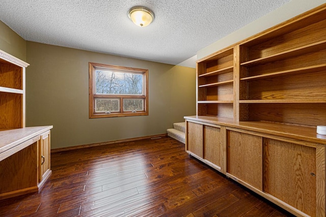 unfurnished office with baseboards, dark wood-type flooring, and a textured ceiling