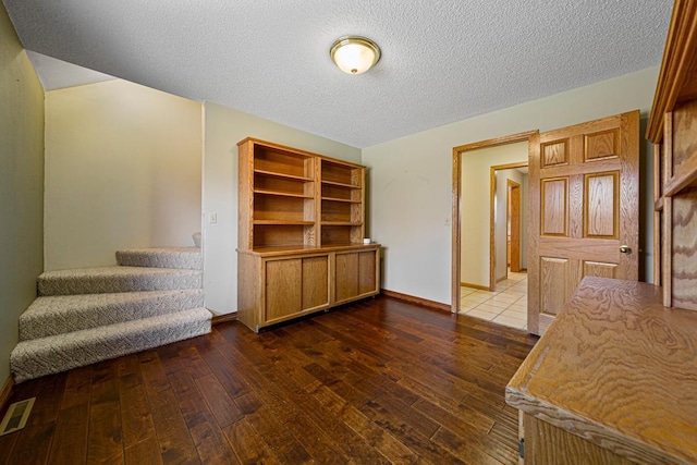 interior space with hardwood / wood-style flooring, visible vents, baseboards, and a textured ceiling