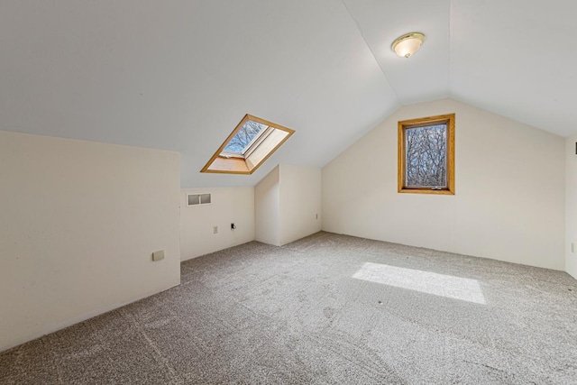 additional living space with visible vents, carpet flooring, and vaulted ceiling