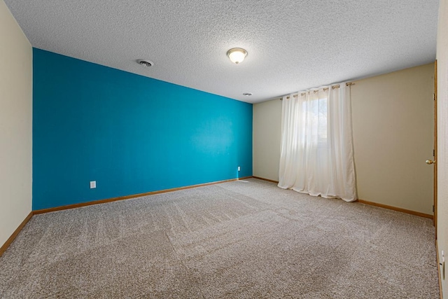 carpeted empty room featuring visible vents, baseboards, and a textured ceiling