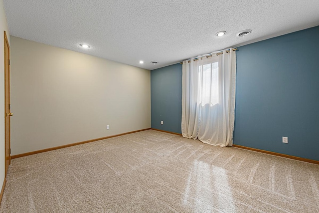 carpeted spare room featuring visible vents, baseboards, and a textured ceiling