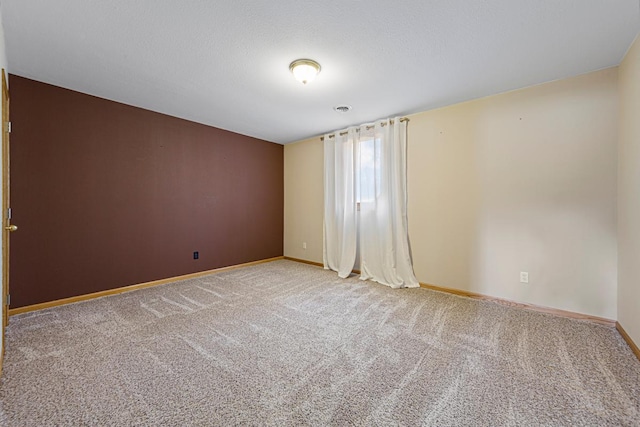 carpeted spare room with a textured ceiling and baseboards