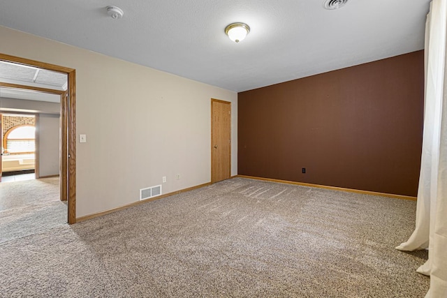 carpeted empty room featuring baseboards and visible vents