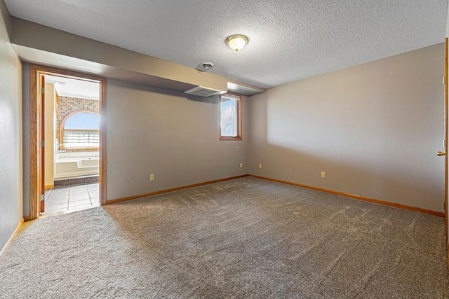 unfurnished room featuring a healthy amount of sunlight, a textured ceiling, baseboards, and carpet floors