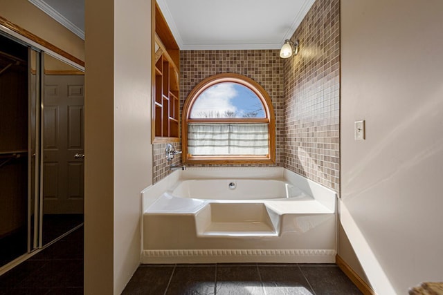 bathroom featuring a bath, tile patterned floors, baseboards, and ornamental molding