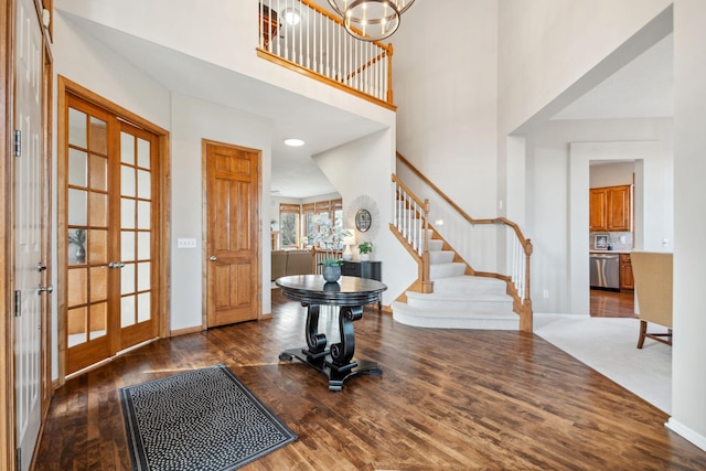 foyer entrance with a chandelier, stairway, baseboards, and wood finished floors