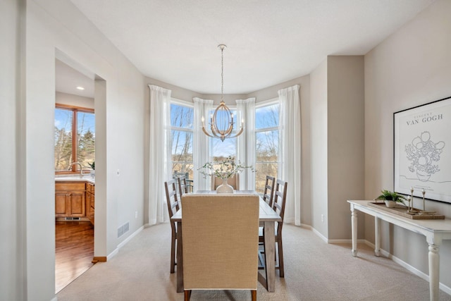 dining space with baseboards, a chandelier, and light carpet