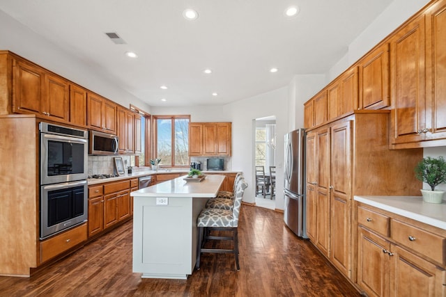 kitchen featuring a center island, light countertops, decorative backsplash, a kitchen breakfast bar, and stainless steel appliances