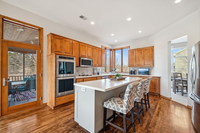 kitchen with decorative backsplash, dark wood-type flooring, appliances with stainless steel finishes, and light countertops