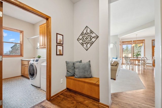 clothes washing area with baseboards, cabinet space, independent washer and dryer, and wood finished floors